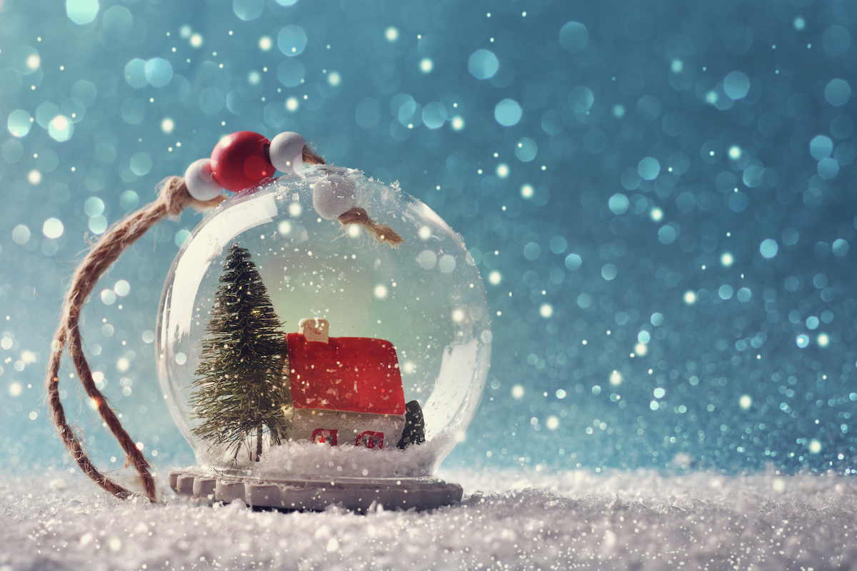 A snow globe ornament against a snowy background.