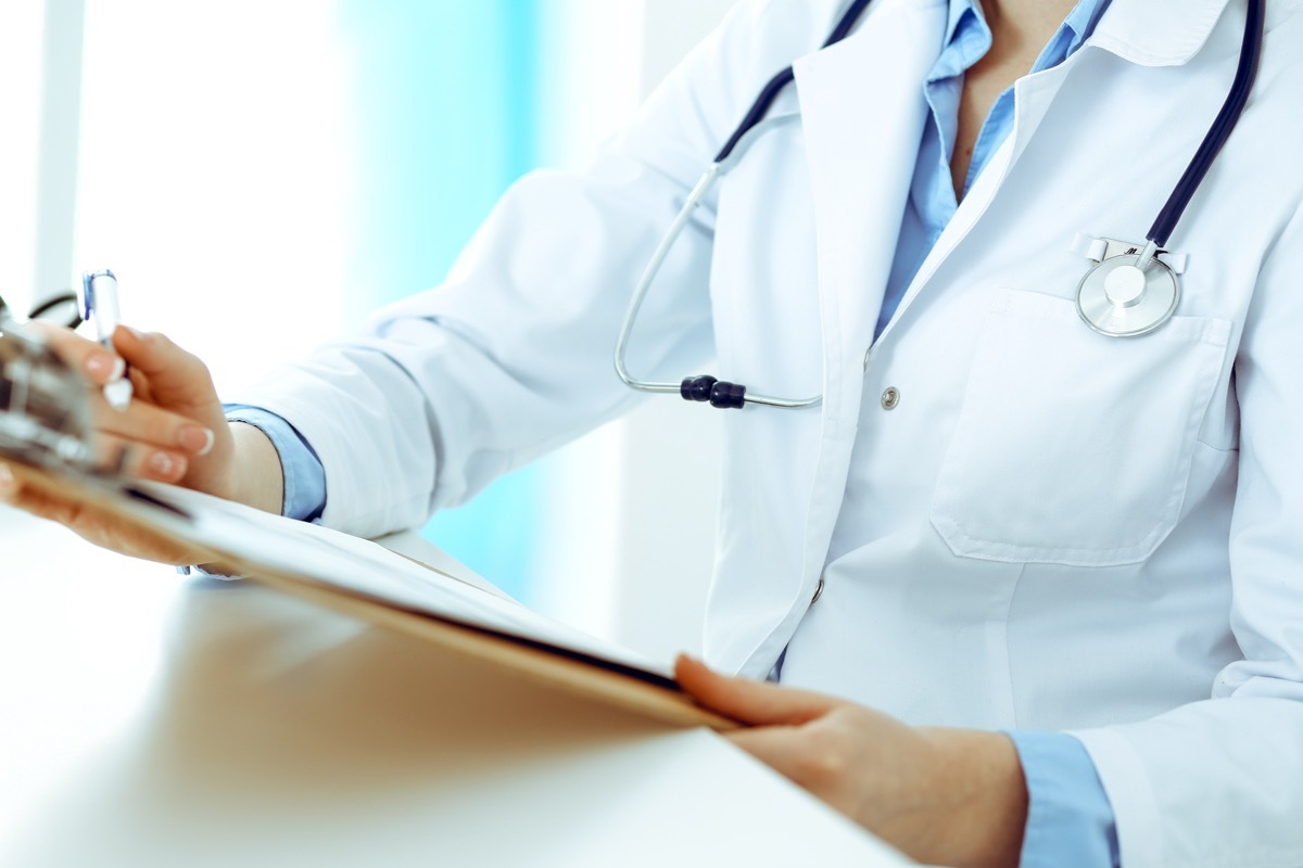 Female doctor using medical form on clipboard closeup