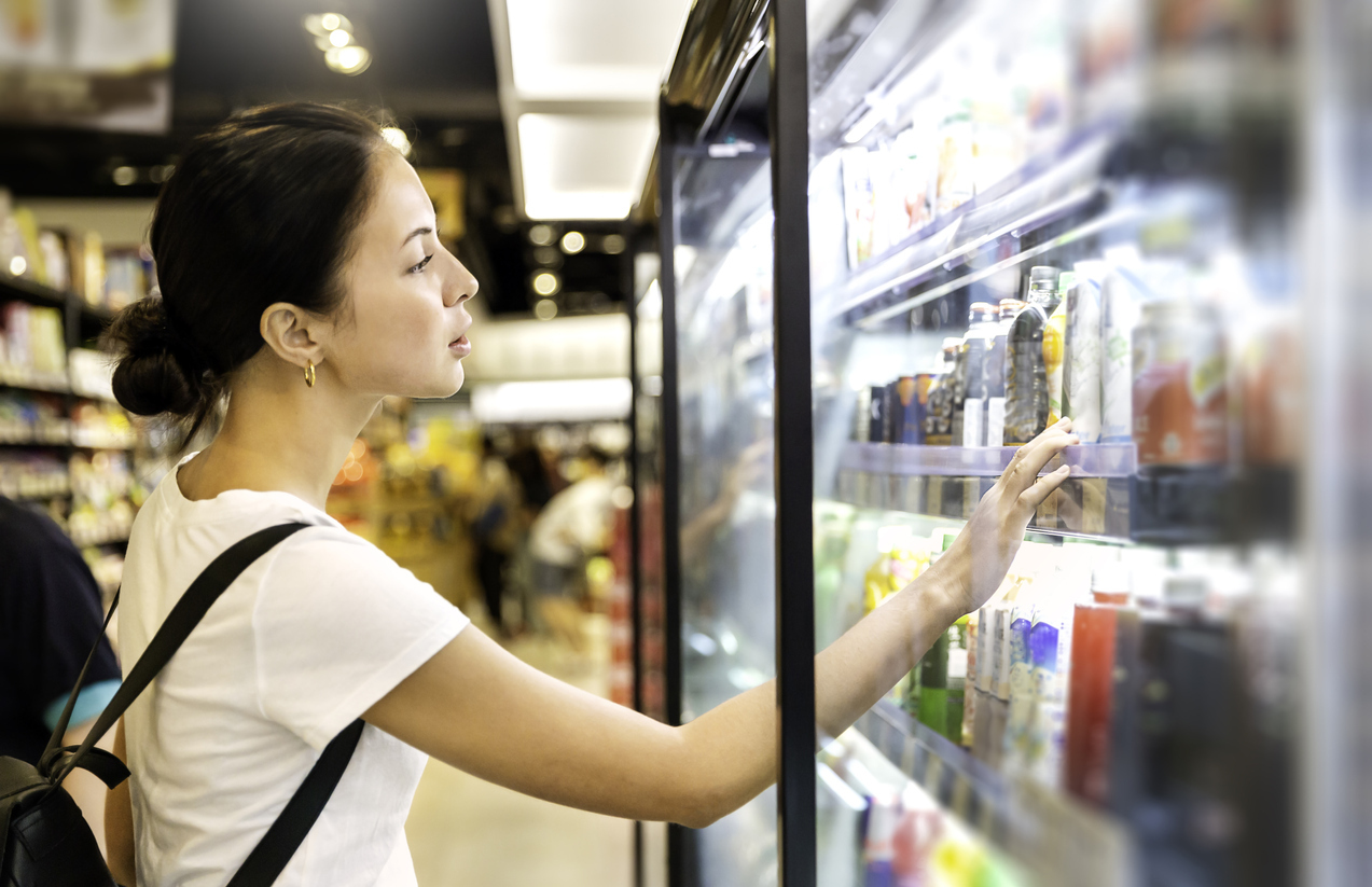 A woman buying a canned beverage at a grocery store