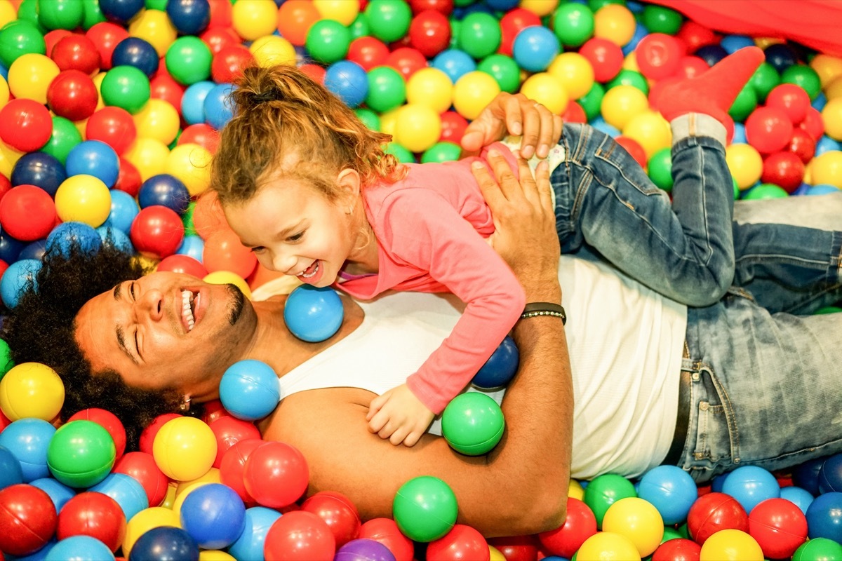 father playing with his daughter inside ball pit swimming pool