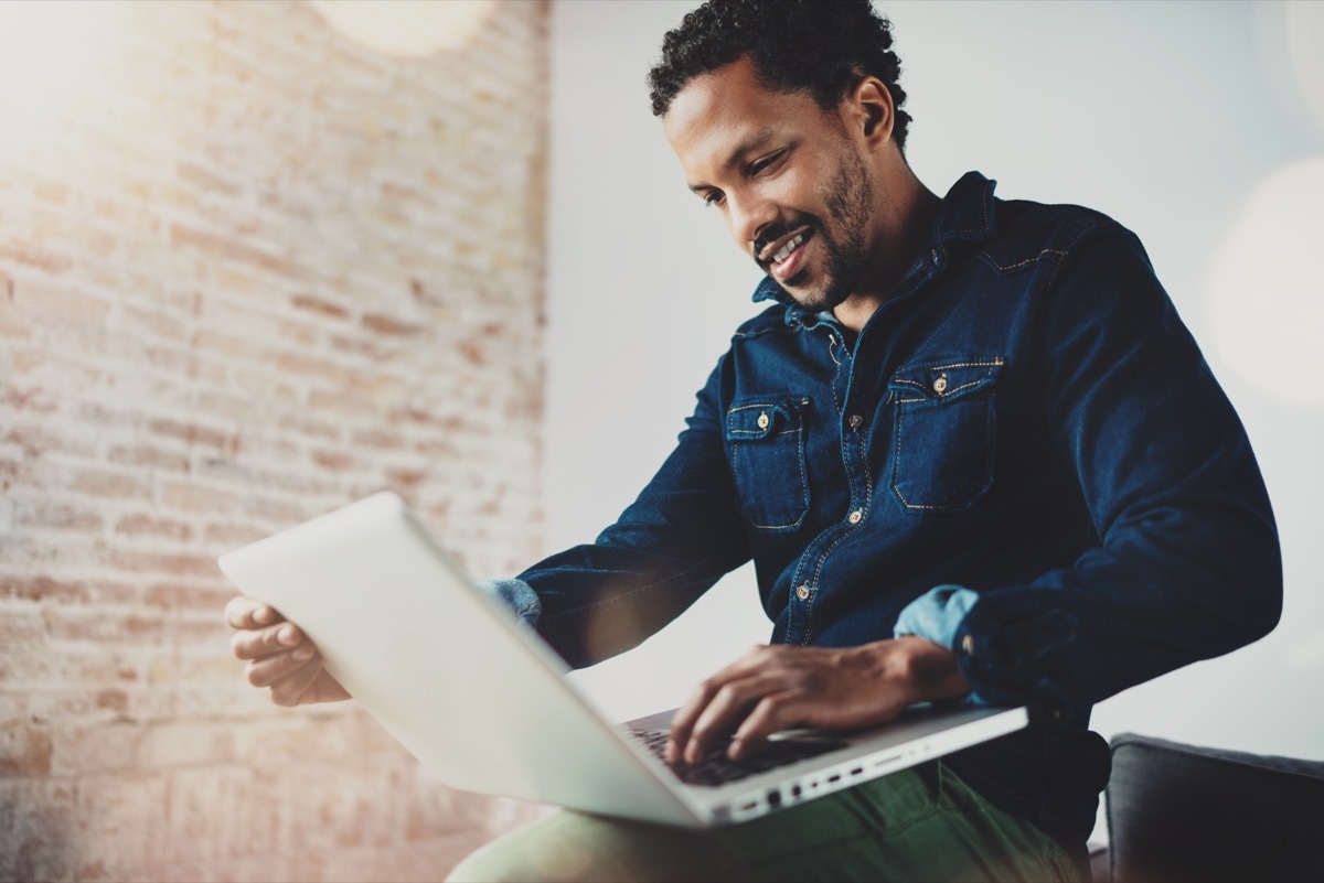 Man smiling scrolling on laptop