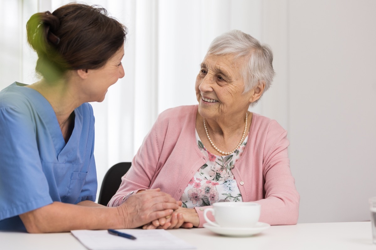 senior woman with caregiver and cup of tea