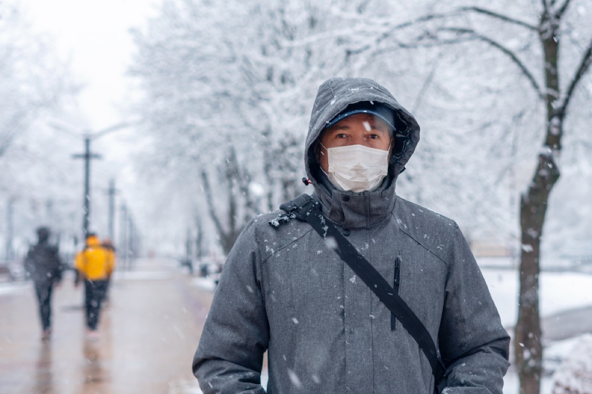 man wearing a face mask outside in a park in the winter