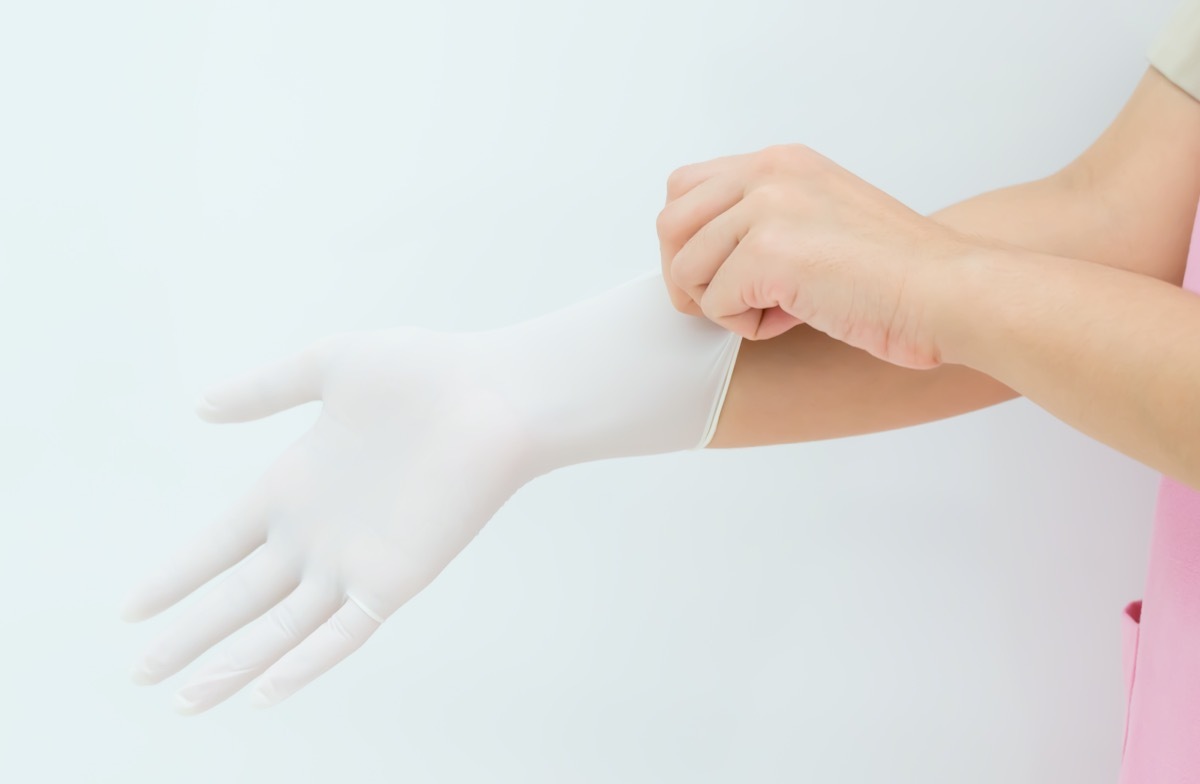 Doctor or nurse putting on protective gloves, on light background,woman surgeon doctor wear glove before operation.