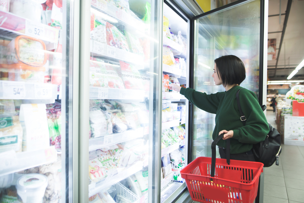 A woman shopping in the freezer section of a grocery store