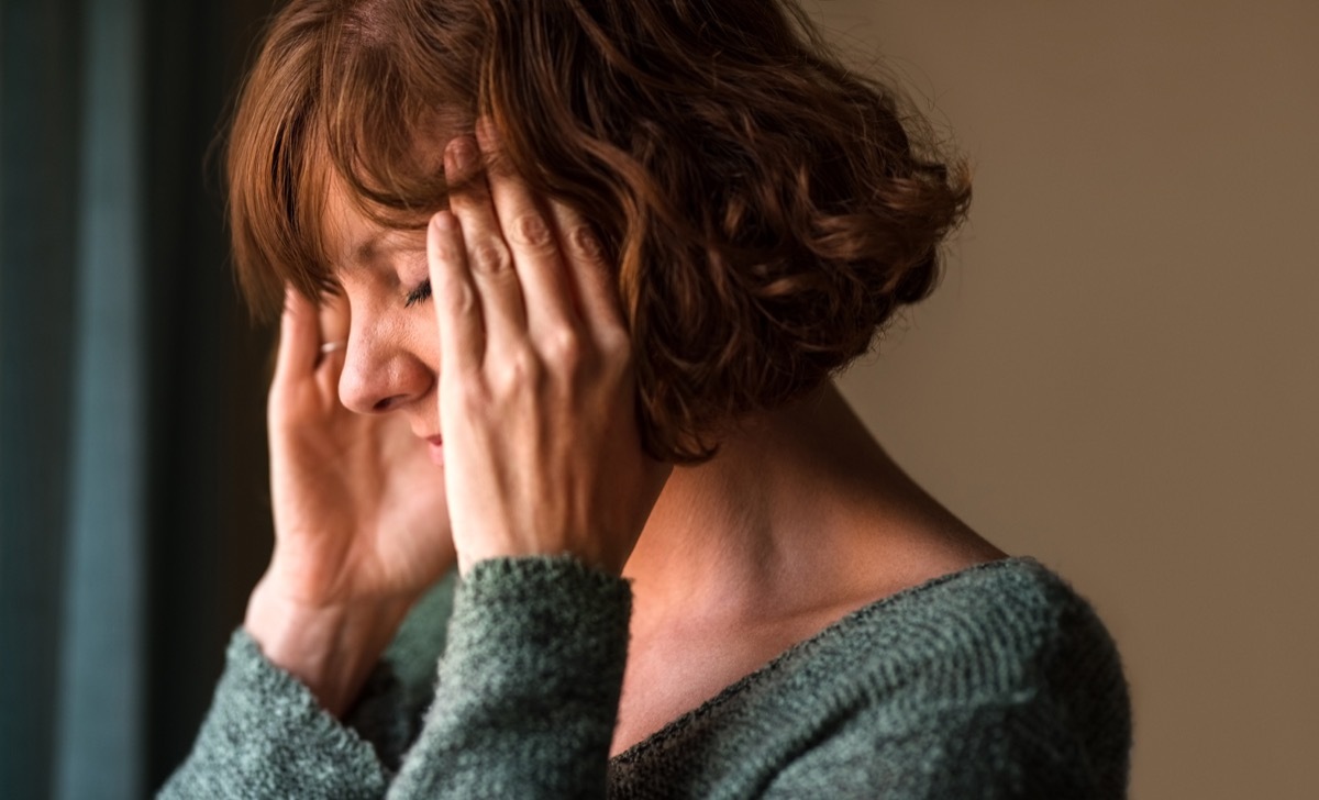 Close-up shot of a woman suffering from a headache and rubbing her temples at home