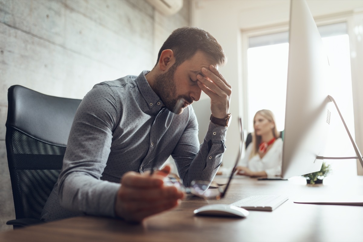 frustrated and stressed businessman sitting at the office front a computer and holding head