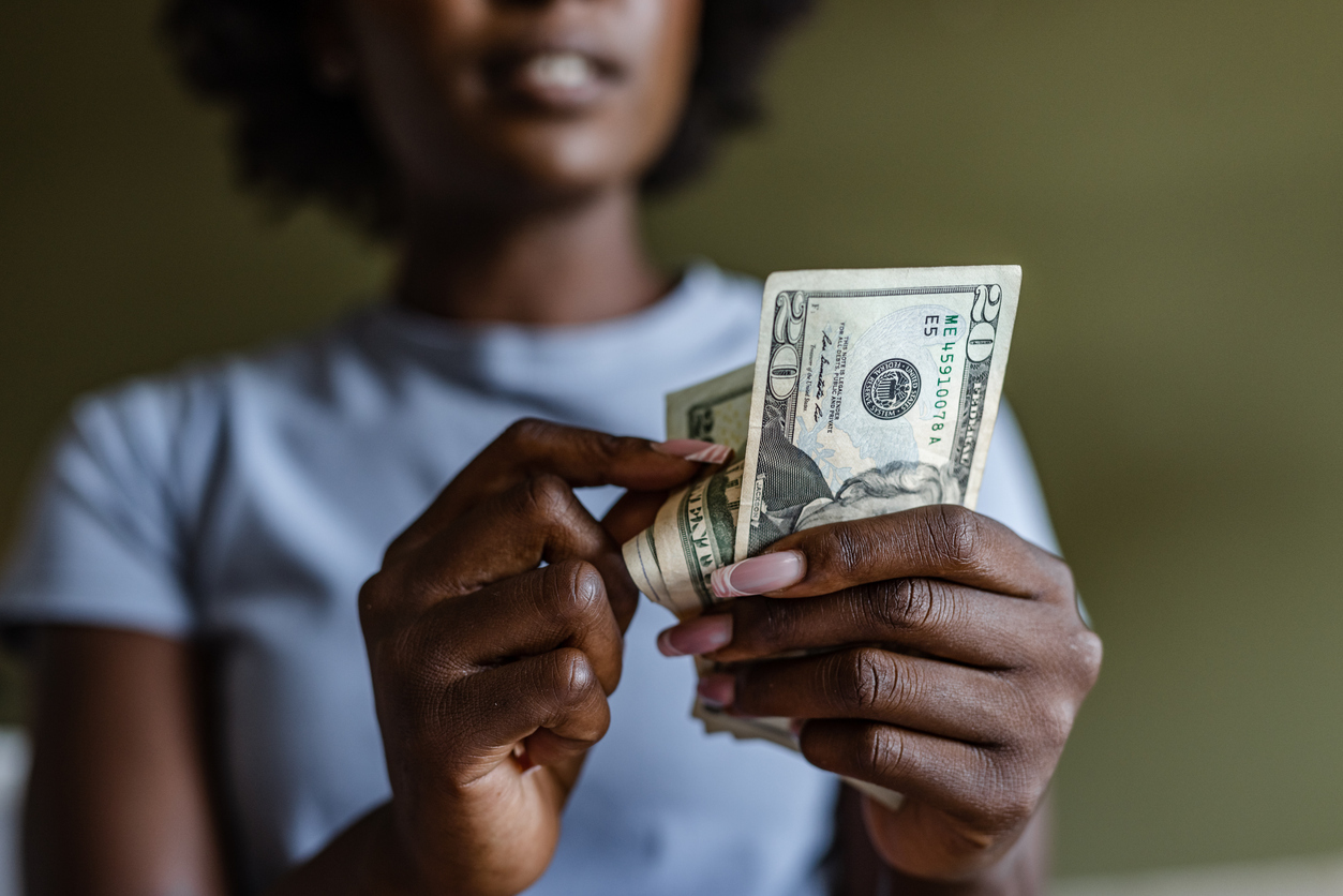 A closeup of a person counting and using $20 bills