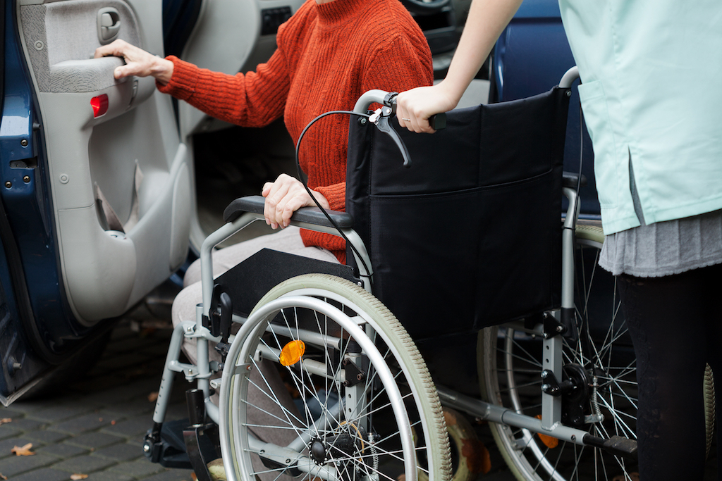 woman helping a patient get into her wheelchair