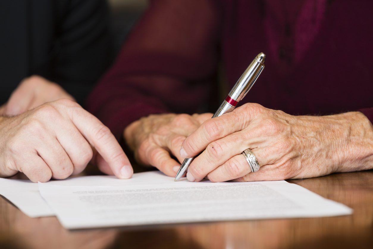 A senior citizen signing a document.