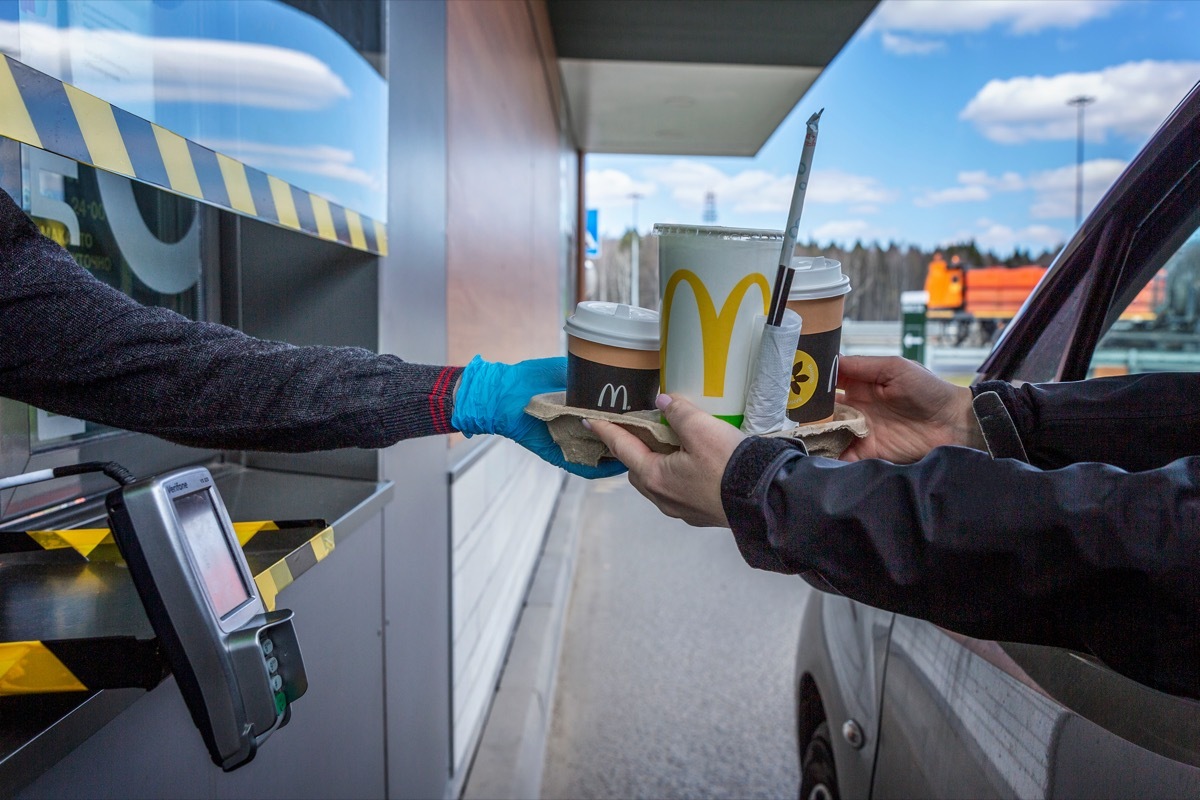 Worker handing order through window at McDonald's drive-thru