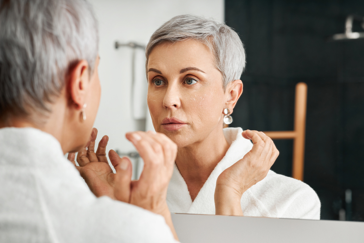 Older woman looking at her reflection in the mirror. 