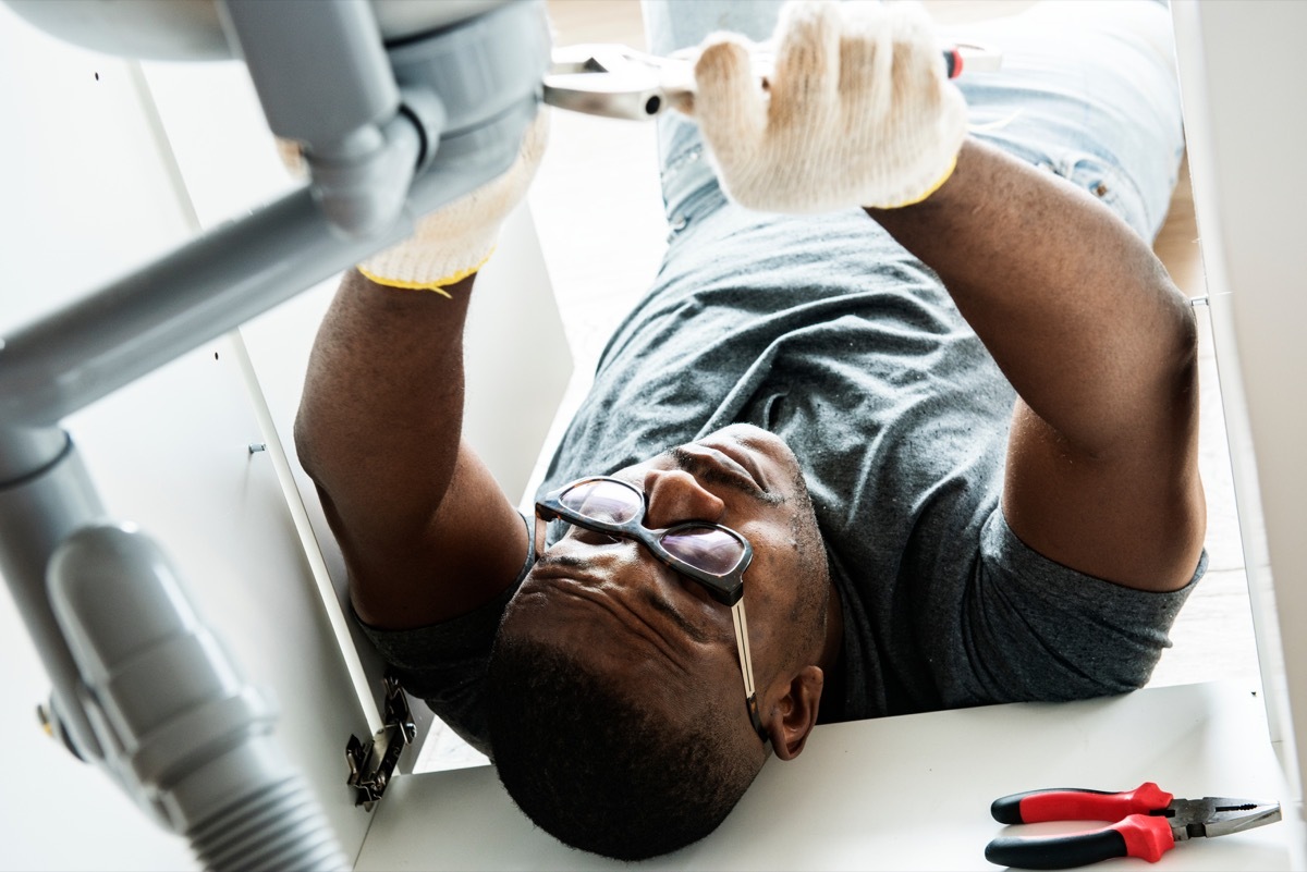 black man fixing sink