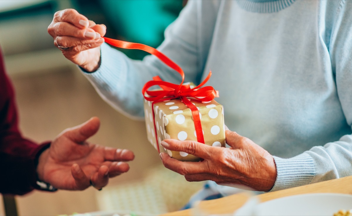 Close-up shot of a lovely senior couple exchanging christmas gifts in dining room.