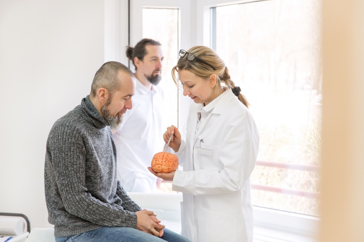 female neurologist is showing a male patient something on a synthetic brain