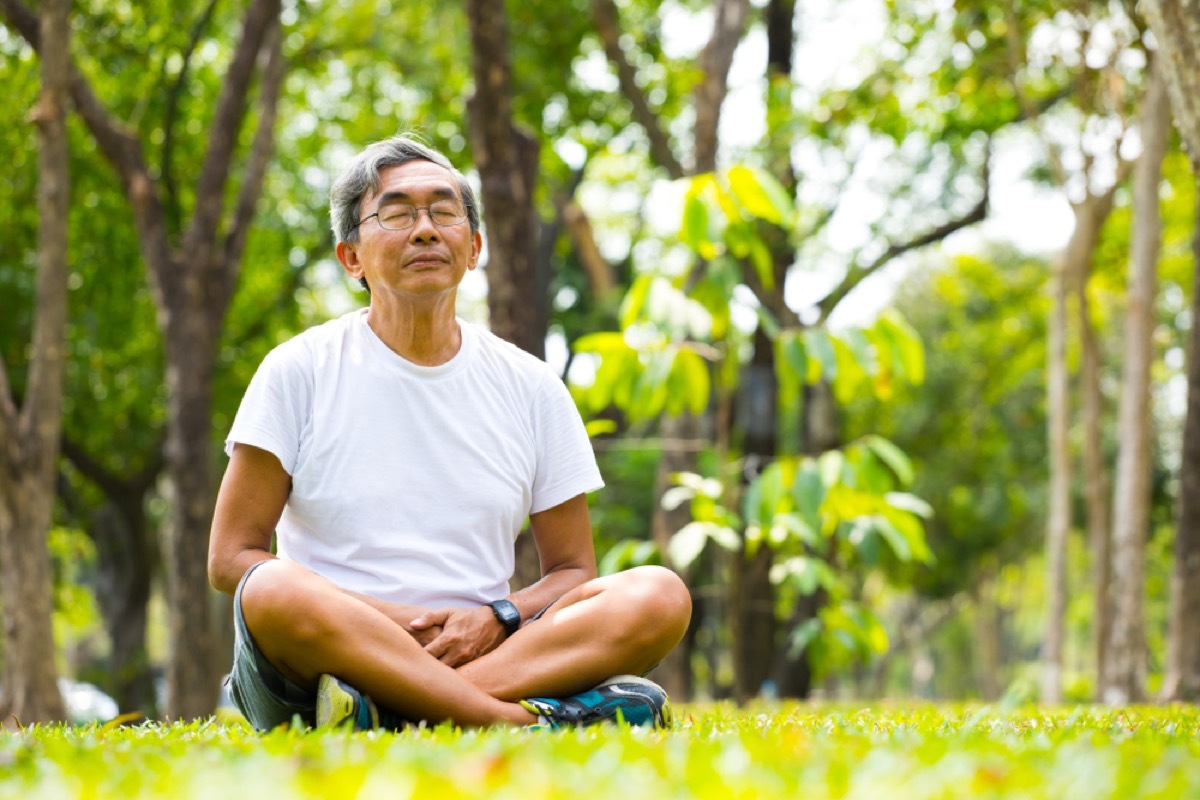 old asian man meditating and practicing meditation in park