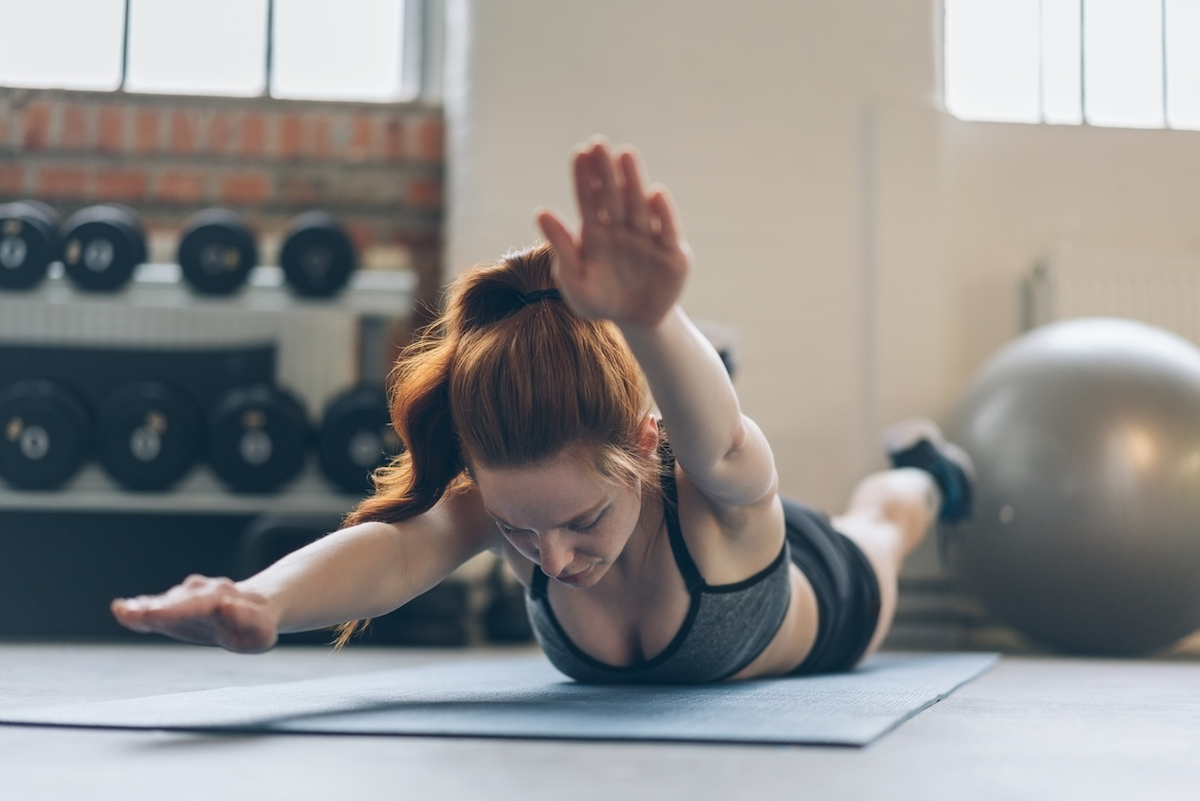 Young woman toning her abdominal muscles working out on a mat in a gym 