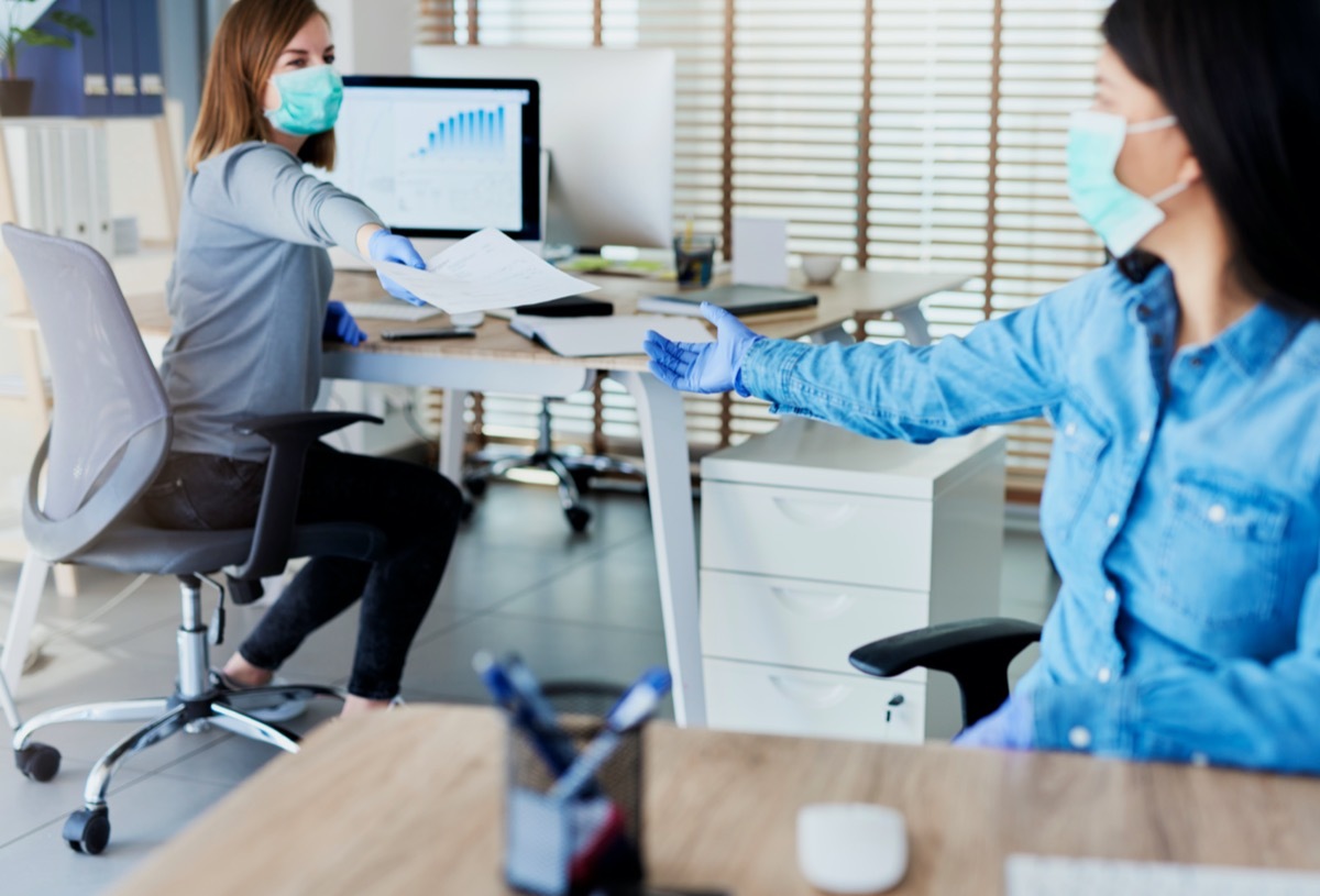 Two people in office passing documents with keeping a distance