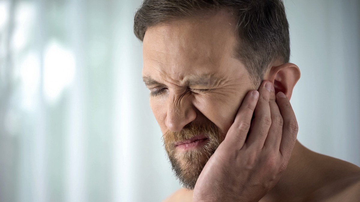 Man holding his mouth because of tooth pain