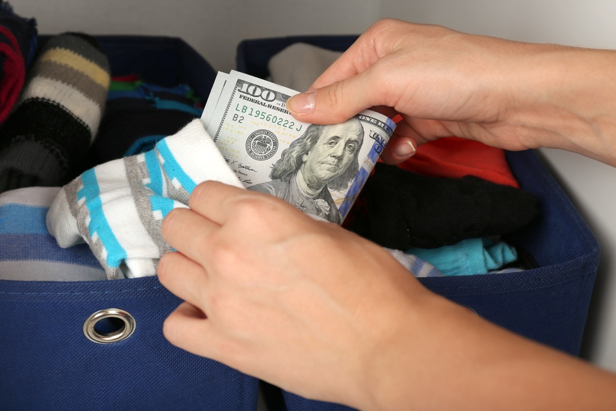 woman's hand places $100 bills in sock, hiding it