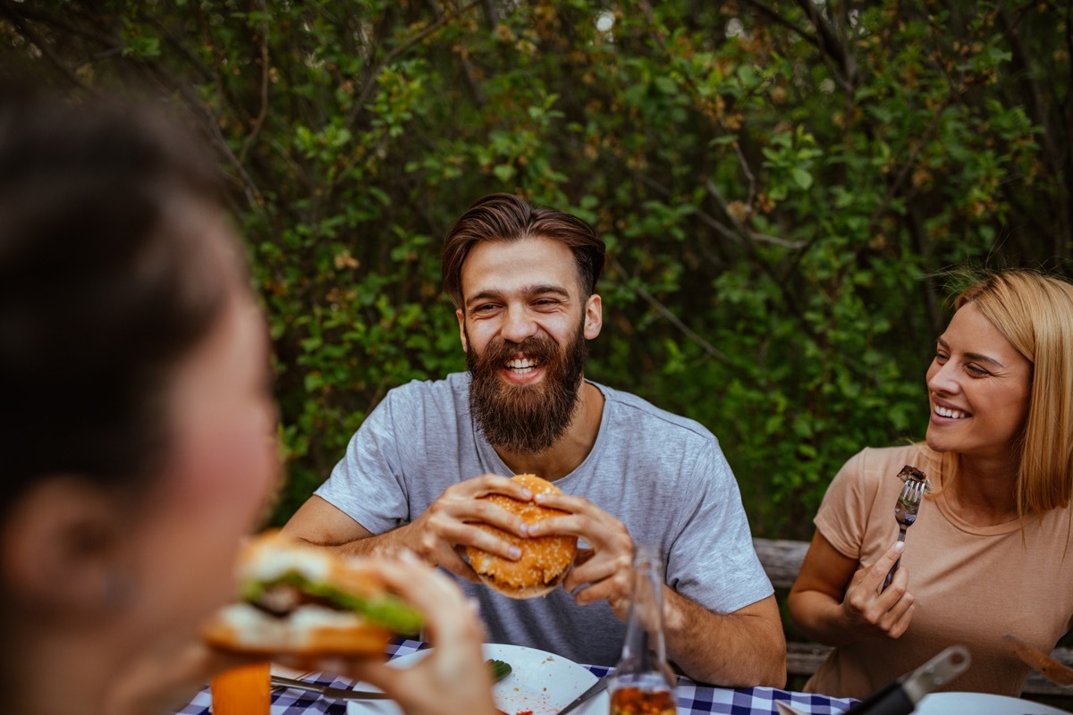 Cropped shot of a young man eating burger outdoors