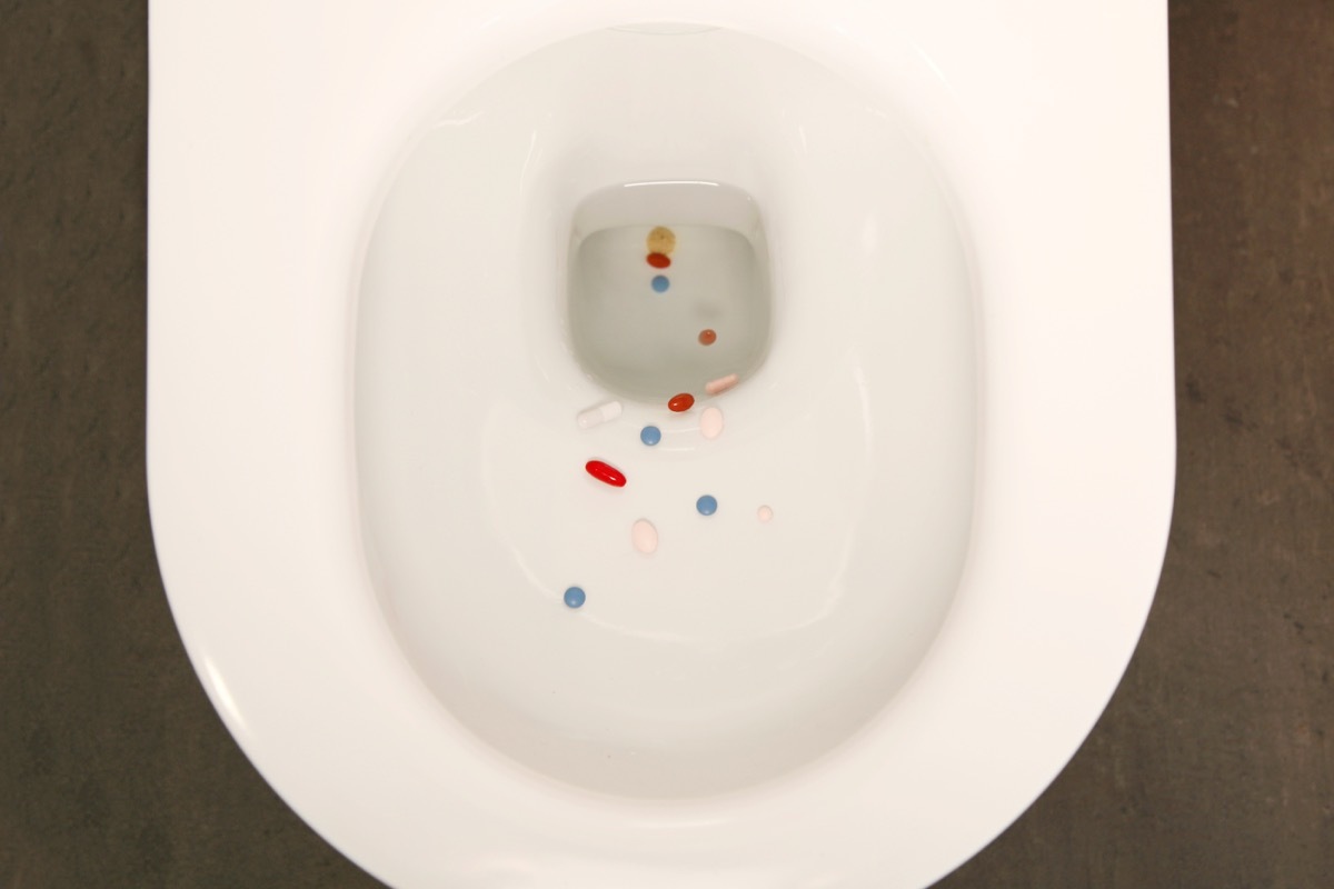 various drugs, medicine, pills getting flushed down a toilet