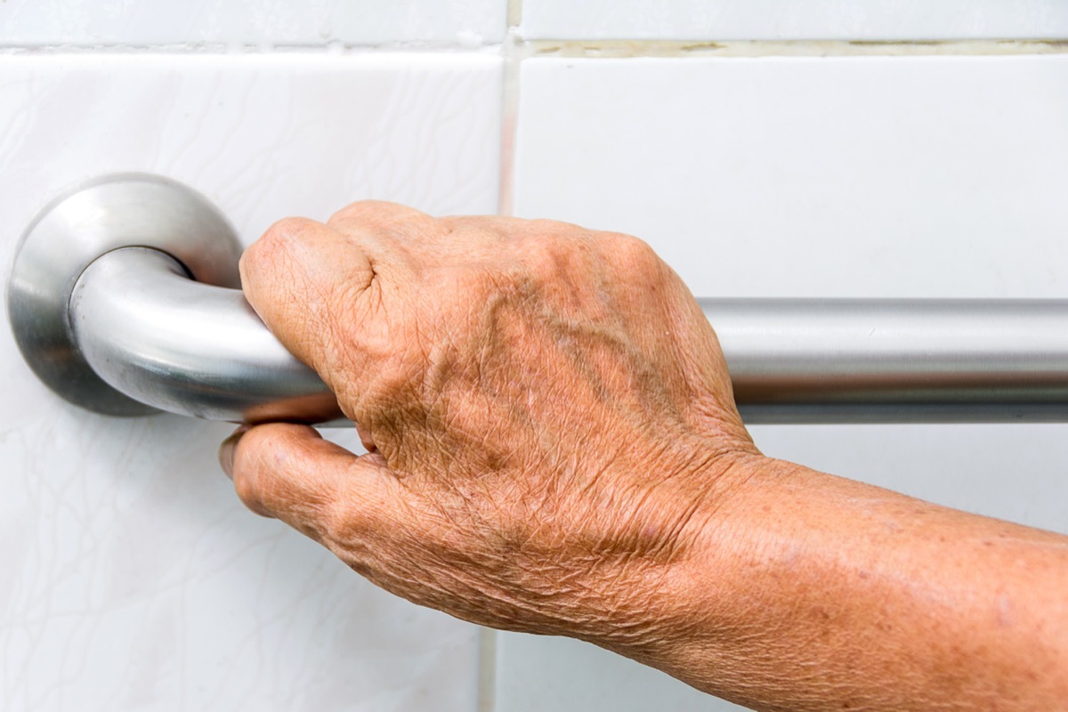 Elderly woman holding a grab bar in a bathroom