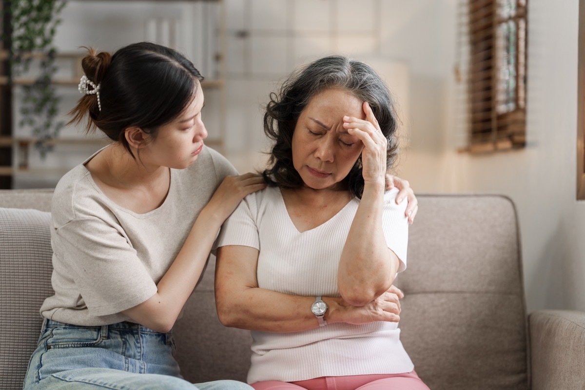 Sad mature woman grown up daughter or grandkid sitting on sofa hugging