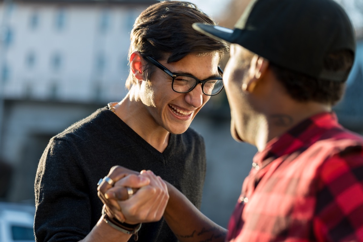 two friends laughing and shaking hands