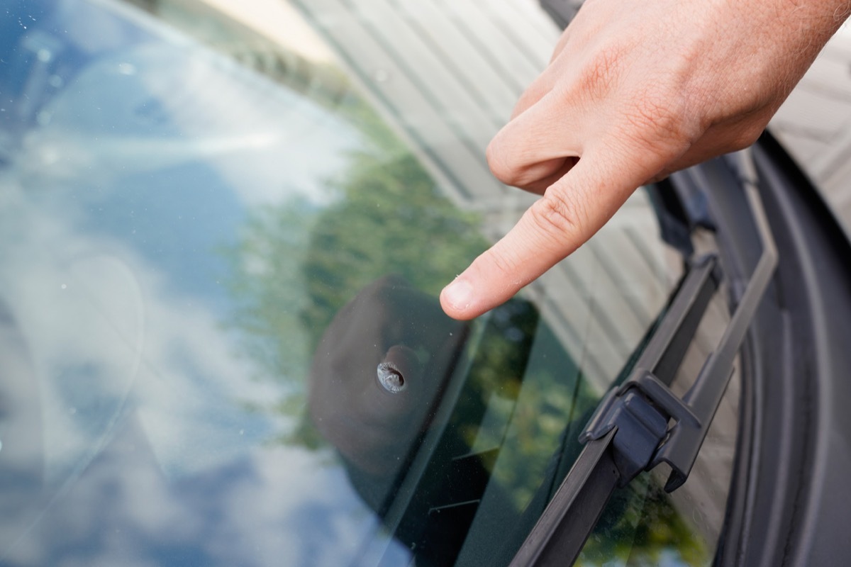 Glazier windscreen on Broken car windshield glass from stone pointed watch of finger hand