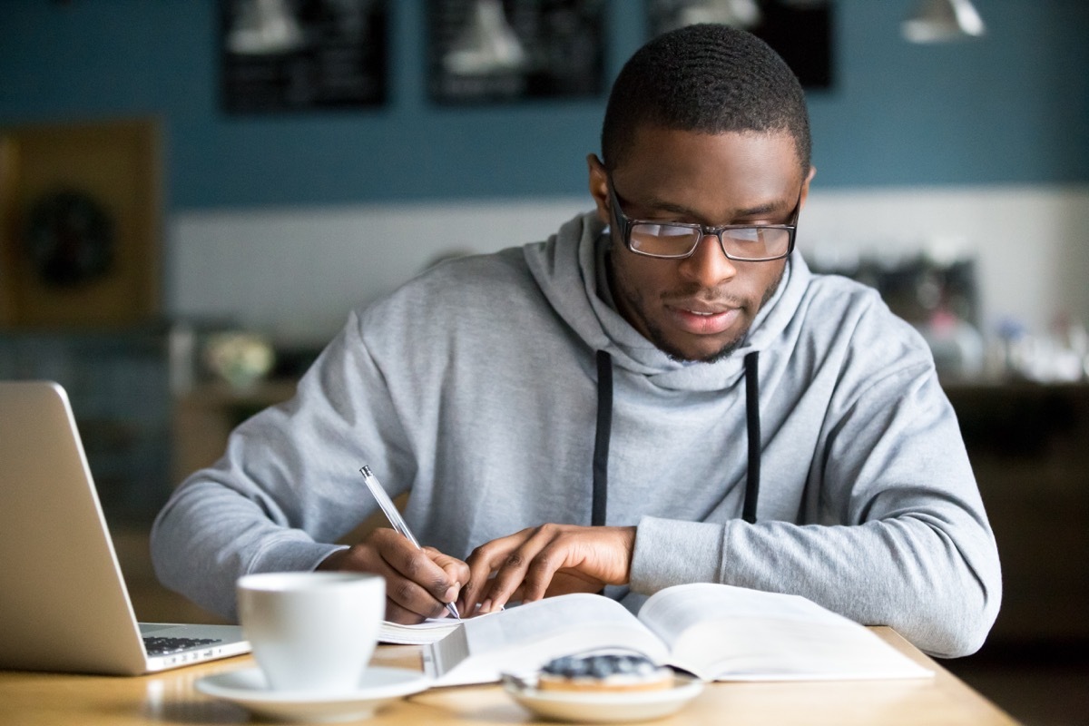 college student studying at a laptop while wearing a hoodie