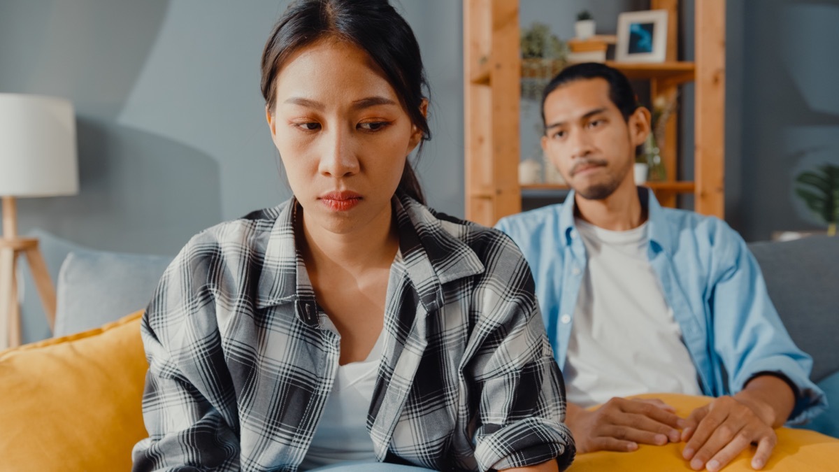 man and woman looking upset fighting on the couch