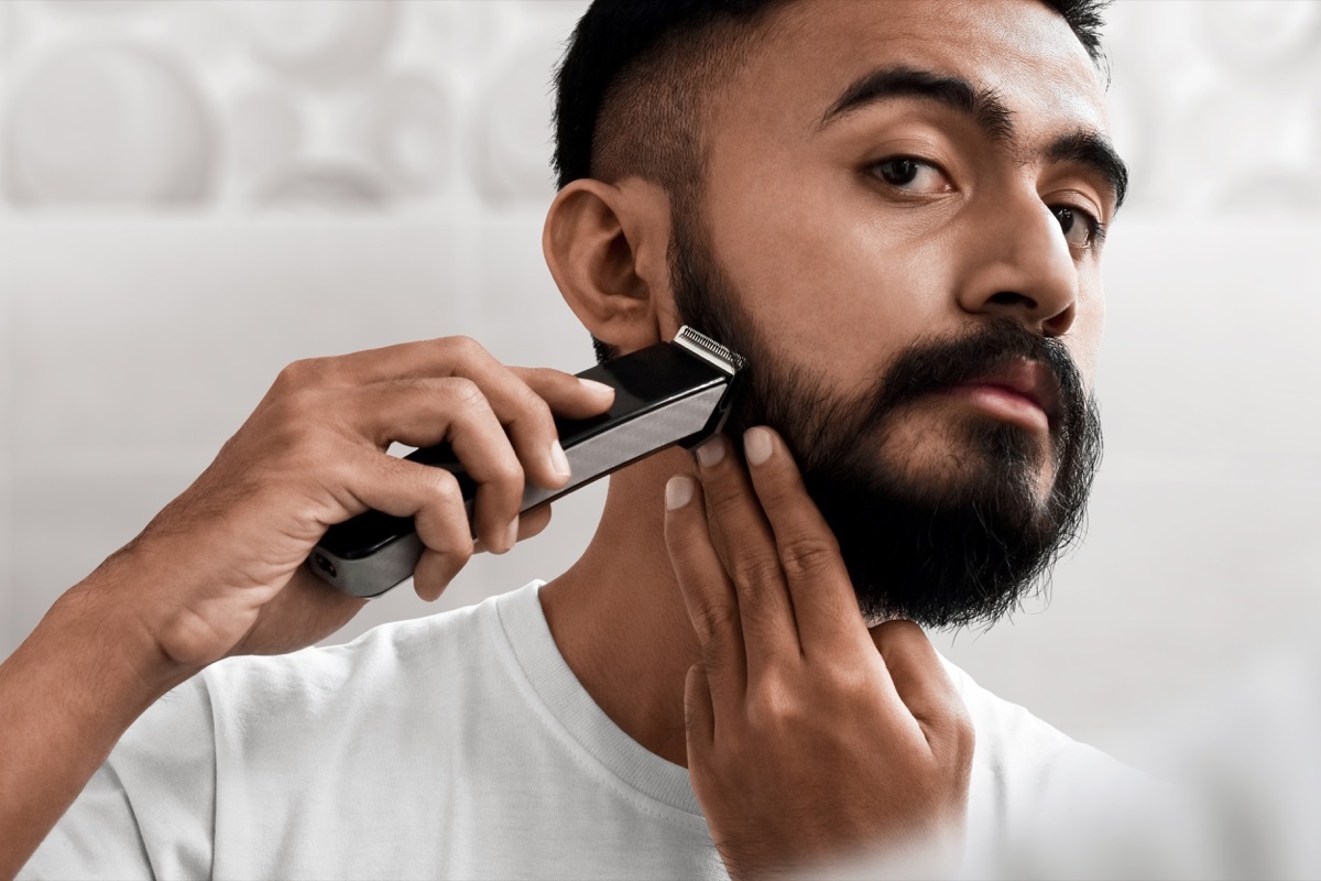 Handsome bearded man shaving his beard