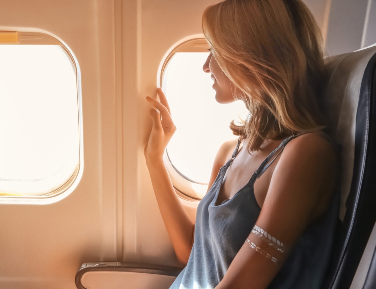 Young woman on passenger seat near window in airplane