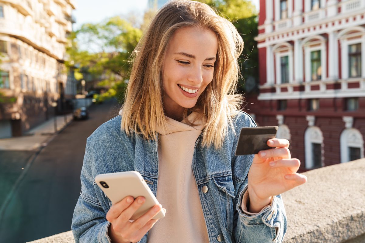 Happy woman shopping on her phone with credit card