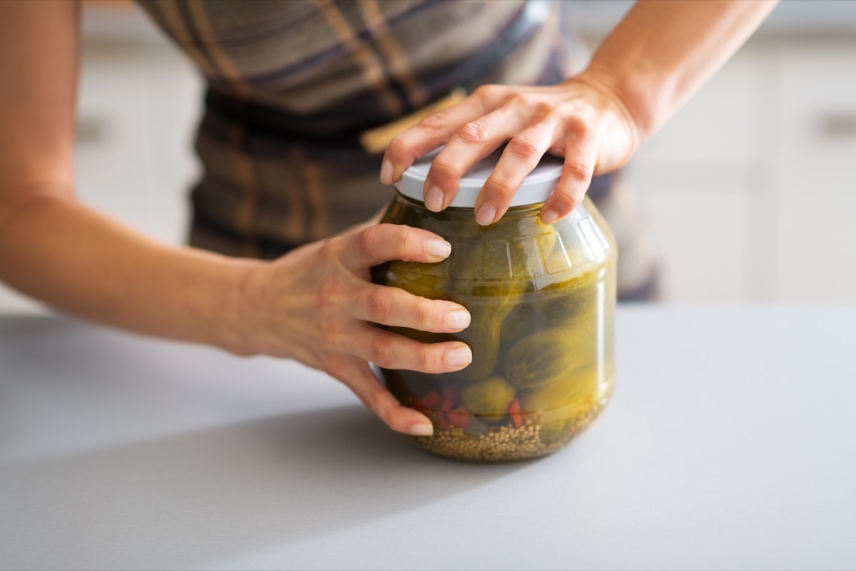 woman trying hard to open a jar of pickles