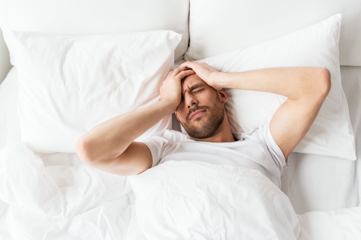 Man in bed with headache