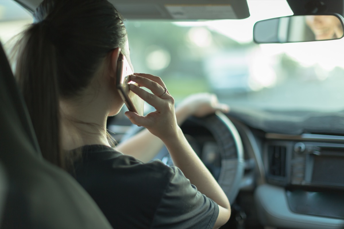 A dangerous female driver using her cellphone and not looking at the road.