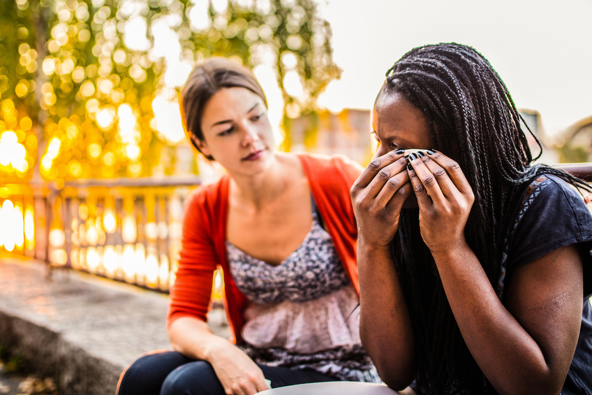 black woman crying while white woman comforts her