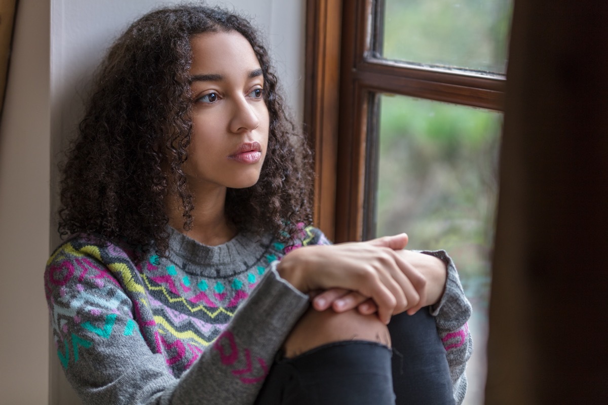 eenager female young woman sad depressed or thoughtful looking out of a window