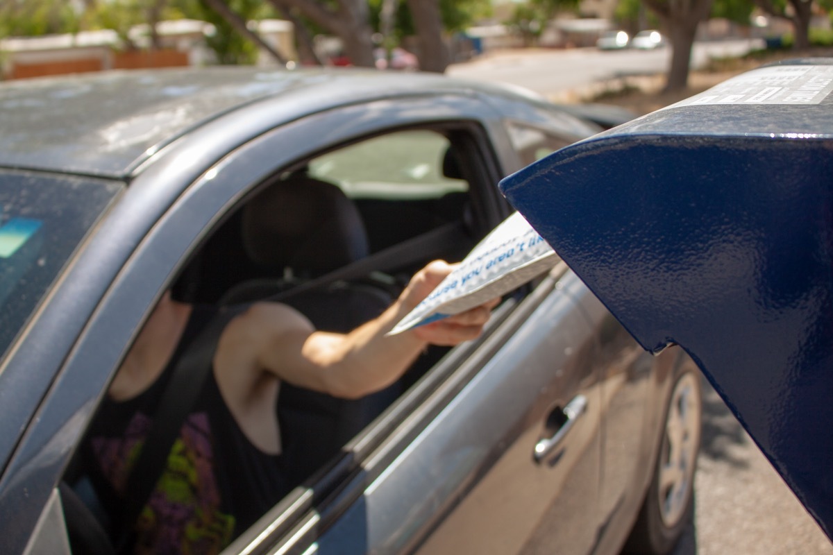 Albuquerque, New Mexico / USA - May 25 2020: Man drops off mail package with eBay envelope from his car at a USPS mail drop box outside the post office