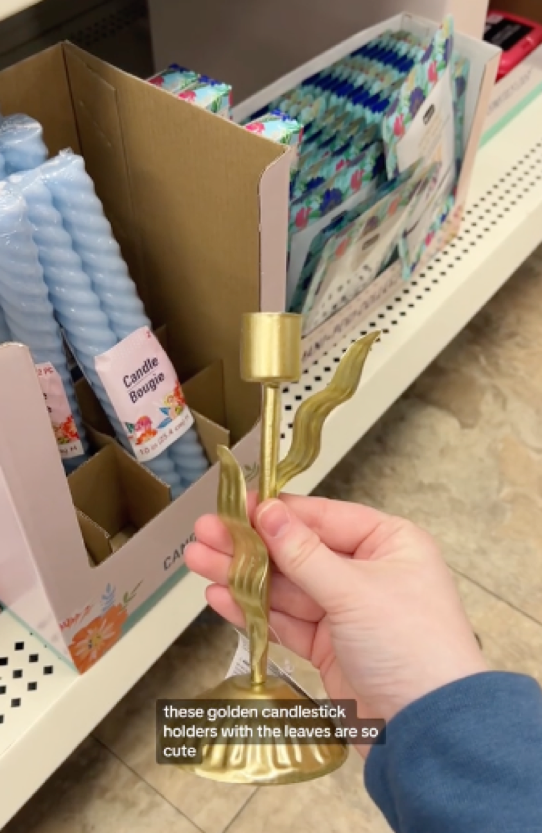 shopper holding gold dollar tree candle holder