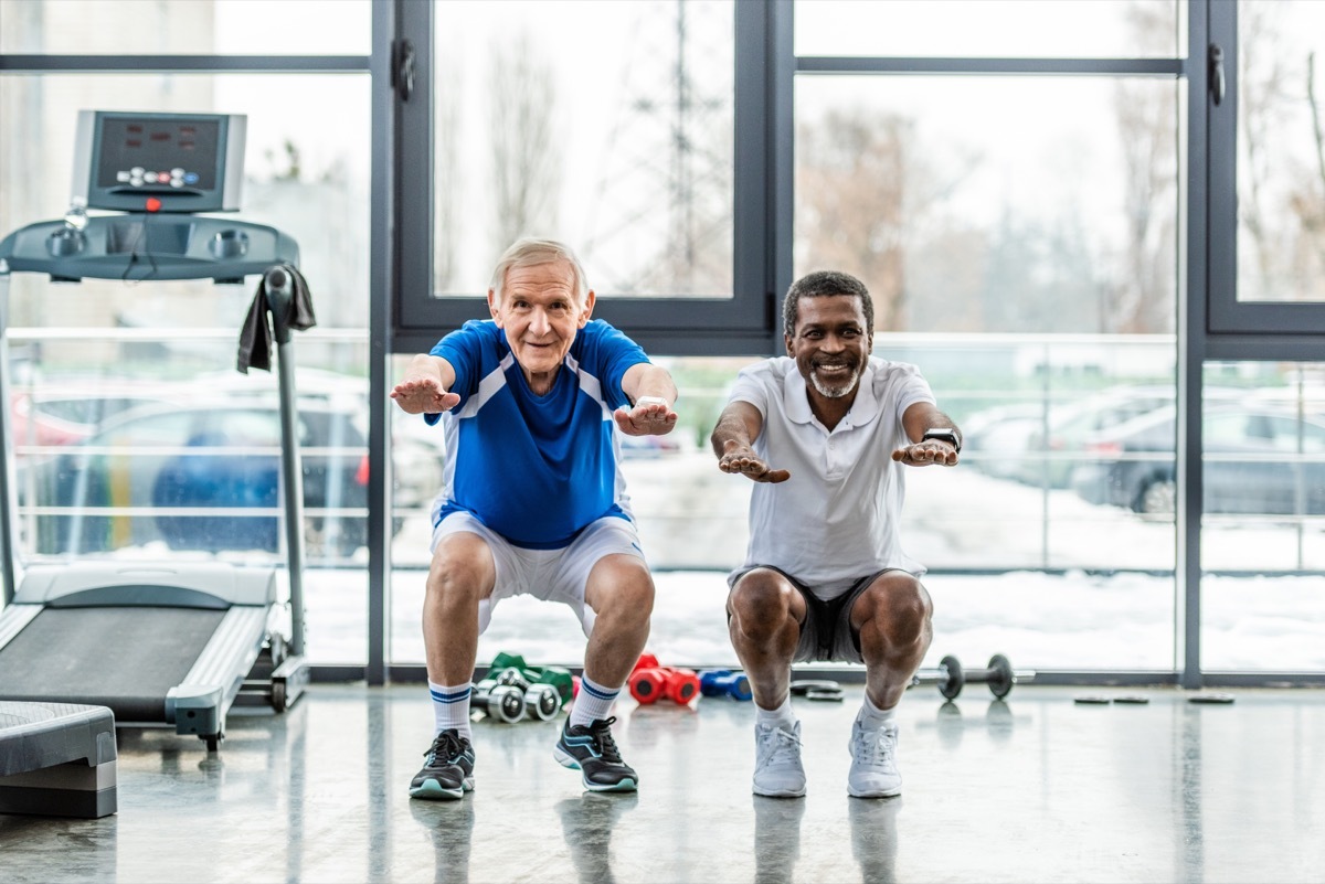 two seniors doing squats at the gym