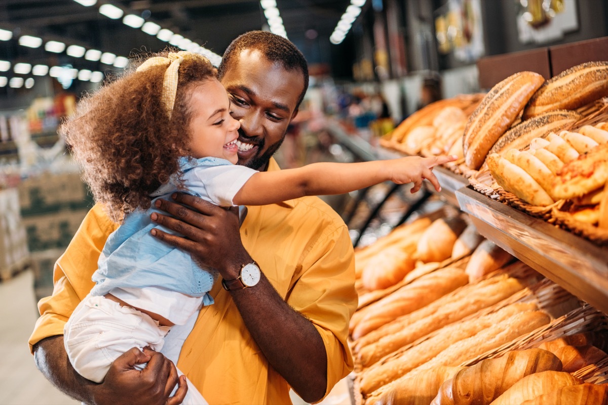 dad and daughter looking at bread in the grocery store