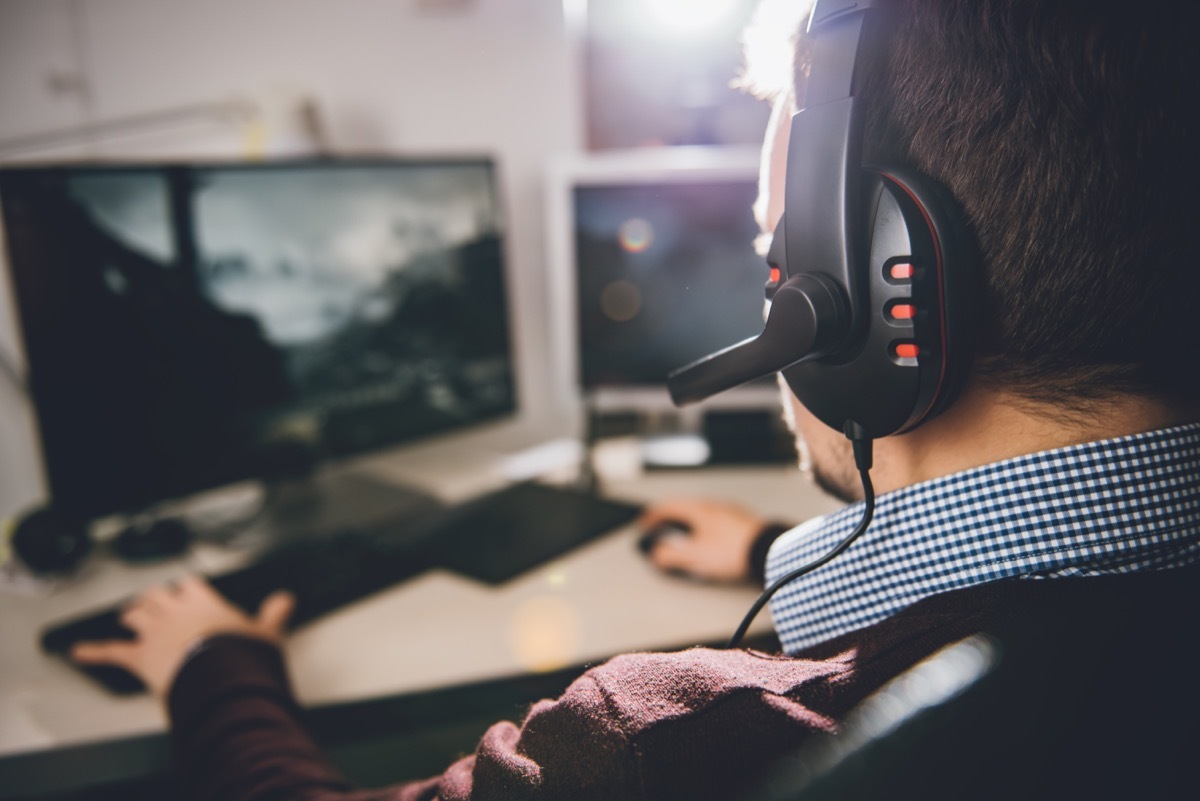 Man wearing a video game headset and playing video games on his computer