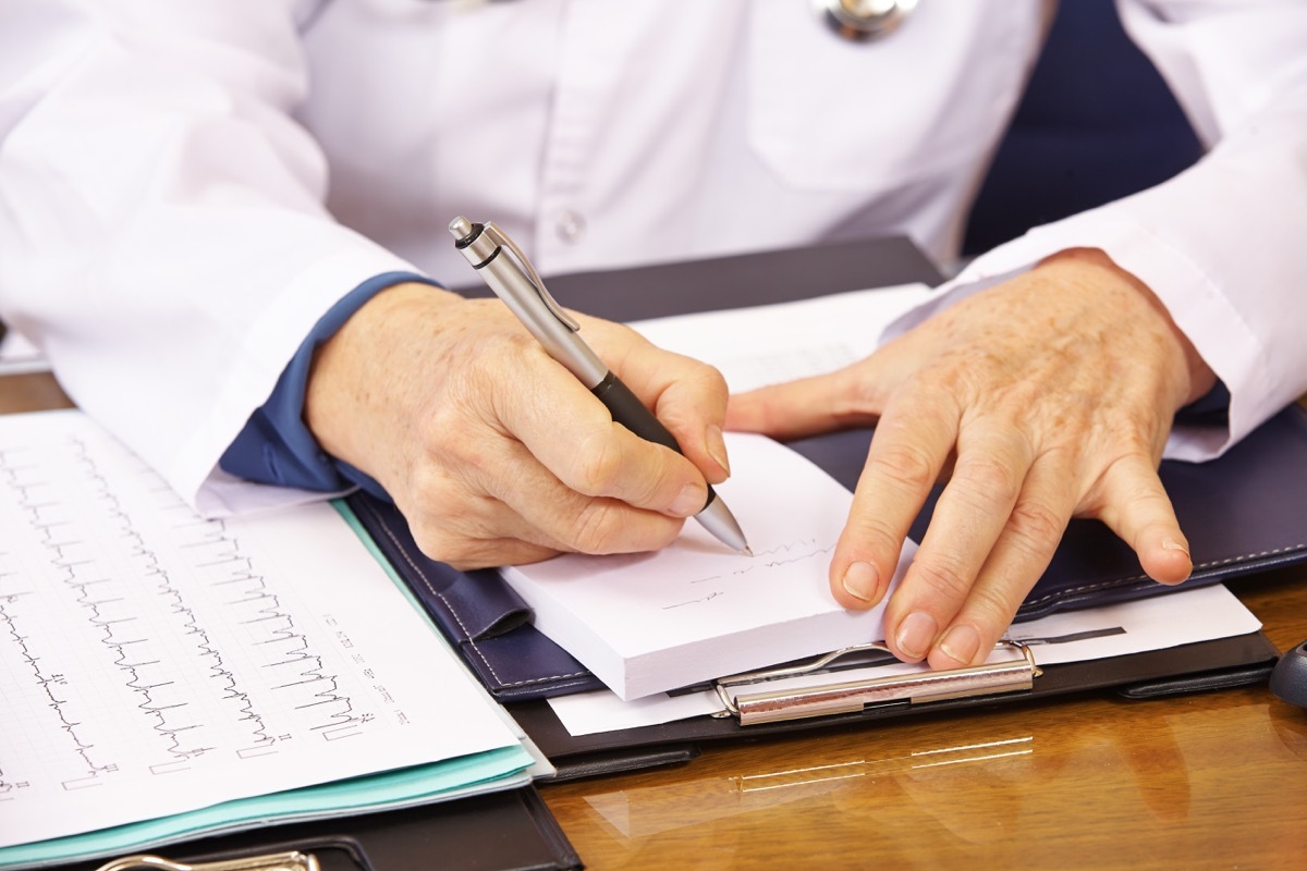 Hand of senior doctor taking notes in office