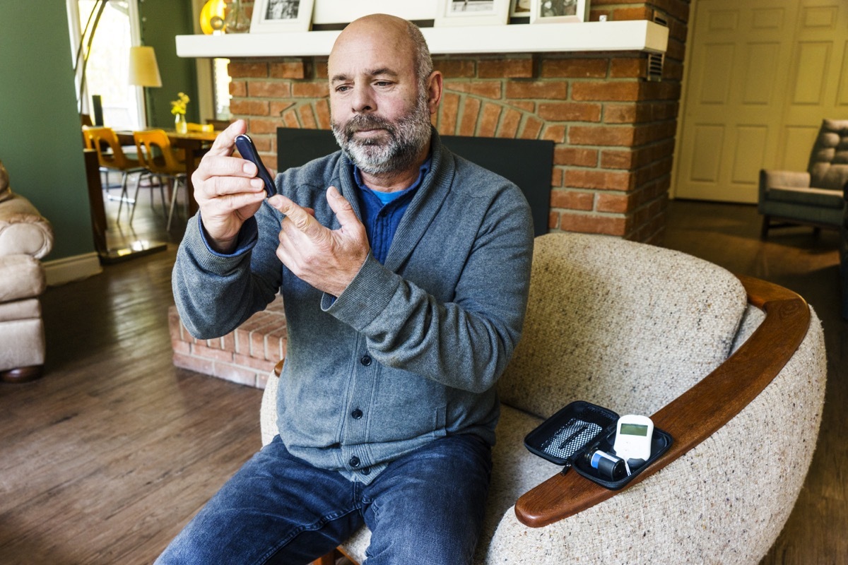 A mature man in his fifties at home testing his blood sugar levels.