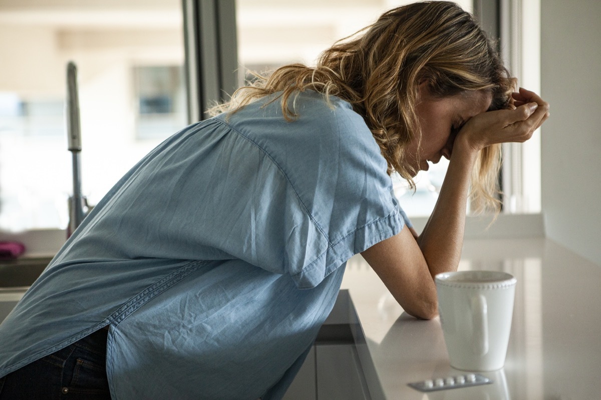 Potrait of stressed woman with head in hands standing indoors during daytime