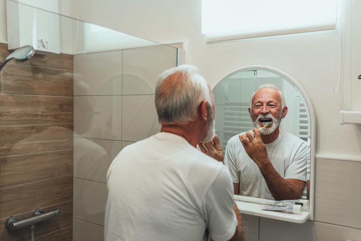 Older man brushes teeth in mirror, things damaging teeth