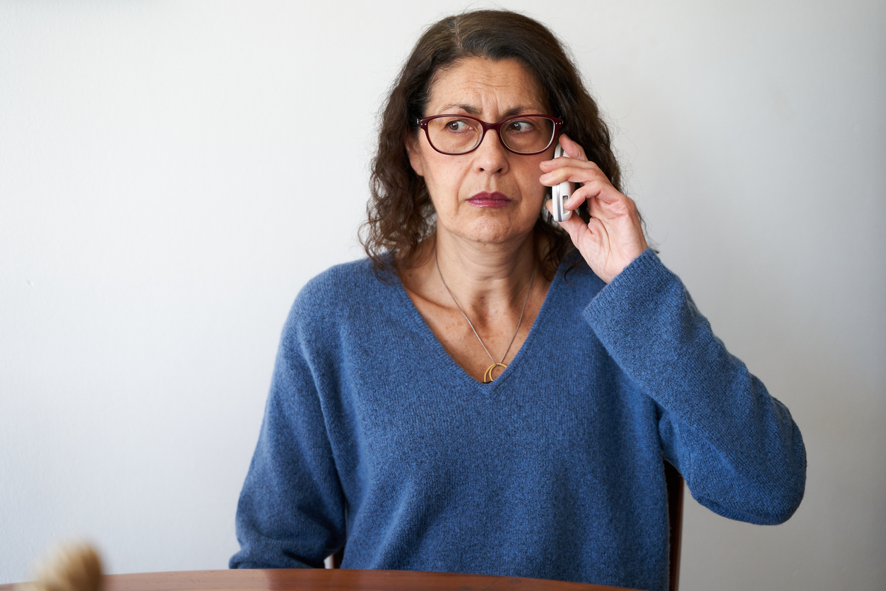 A senior woman on the phone with a suspicious or concerned look on her face